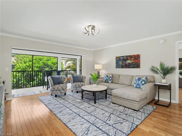Living area with wood-finish flooring, crown molding, and a modern ceiling fixture
