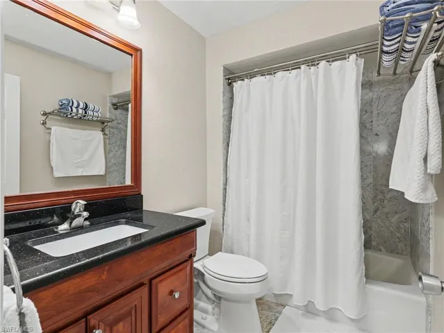 Bathroom featuring a wood-finish vanity with a black countertop, integrated sink, and chrome faucet