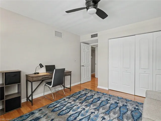 Hardwood-style flooring extends throughout this room, complemented by a ceiling fan with integrated lighting