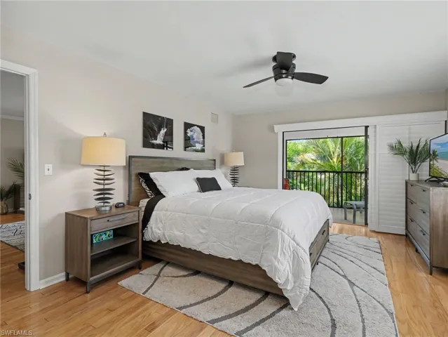 Bedroom featuring wood-finish flooring, a ceiling fan, and a sliding glass door opening to a balcony with black railings