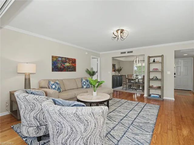 Living area featuring crown molding, hardwood flooring, recessed lighting, and a broad entry to an adjacent dining space