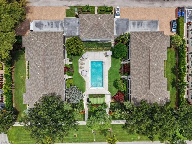 Expansive property featuring three buildings with gabled roofs, a central rectangular swimming pool, and lush landscaping