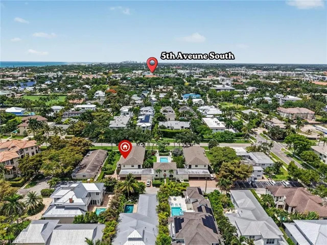 Aerial perspective of a verdant residential area featuring numerous properties with private swimming pools, mature landscaping, and multi-story structures