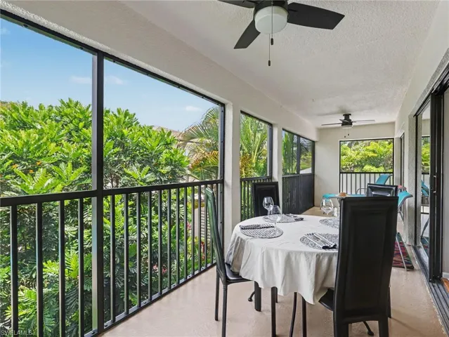 Spacious screened lanai featuring a textured ceiling, dual ceiling fans, and sliding glass door access