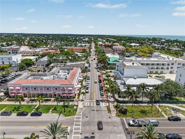 Aerial perspective showcasing a vibrant street lined with diverse architectural styles, including a prominent pink building with arched windows and awnings