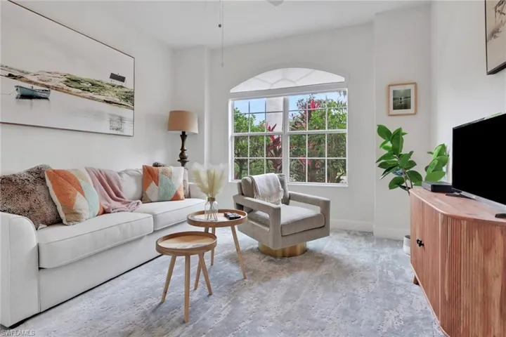 Carpeted living area featuring a ceiling fan and baseboards