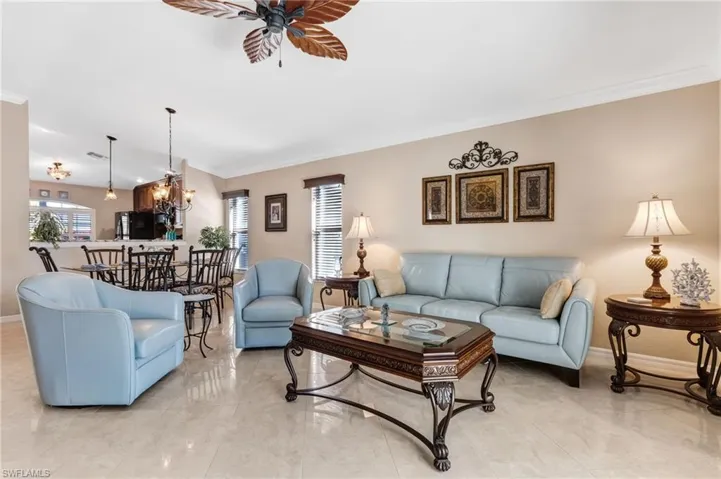 Living room with crown molding, ceiling fan, plenty of natural light, and suspended lighting