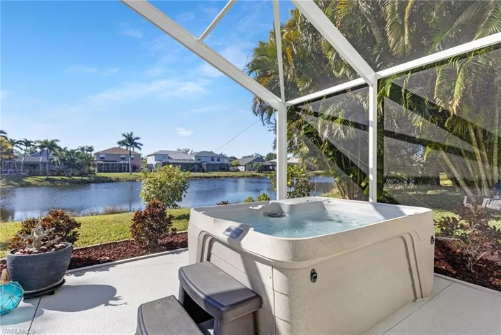 View of patio with a lanai, a lake view, a hot tub