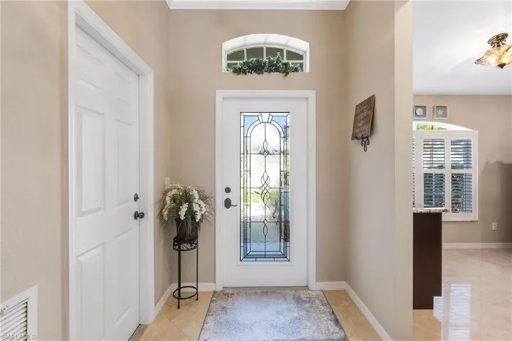 Entryway with crown molding and light tile patterned floors