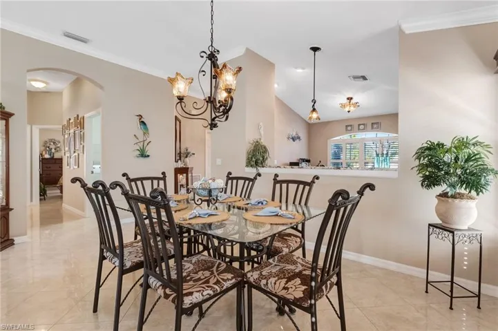 Dining area with crown molding, arched walkways, and a chandelier