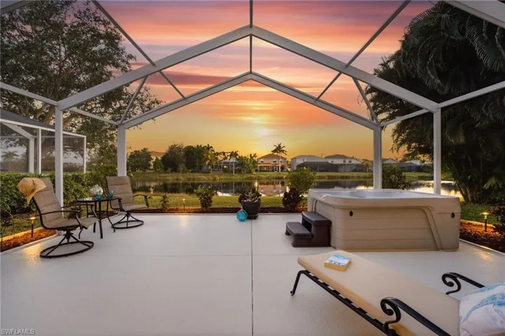 Patio terrace at dusk with a lanai, a hot tub, a sunroom, a patio, and a water view