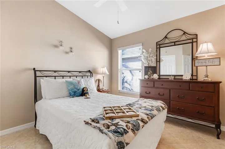 Bedroom with lofted ceiling, a ceiling fan, and light tile patterned flooring