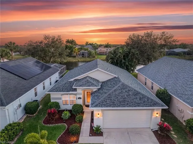 View of front facade with a shingled roof, a garage, a water view, concrete driveway, and stucco siding