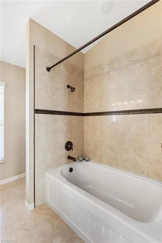 Full bathroom featuring soaker tub / shower combination and tile patterned flooring