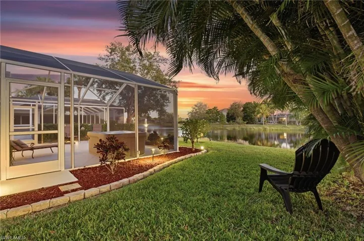 View of grassy yard with a lanai, a sunroom, a water view, and a patio