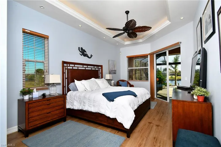 Bedroom with access to outside, multiple windows, ceiling fan, and light hardwood / wood-style floors