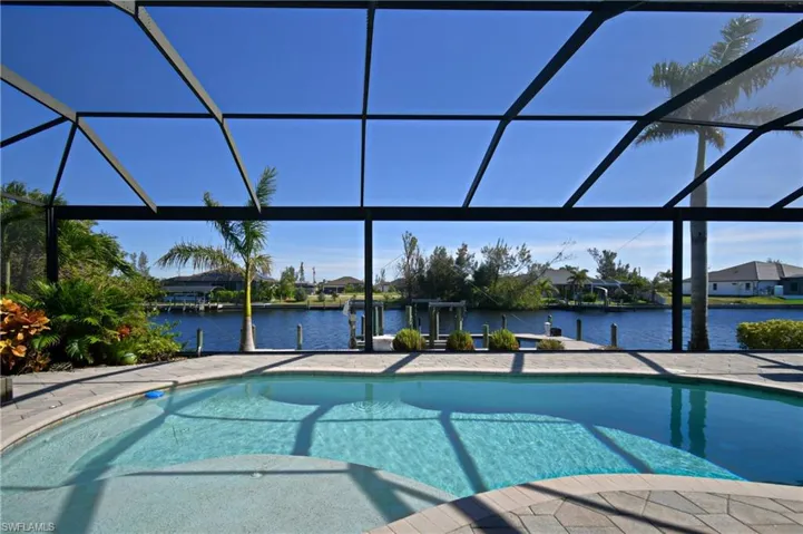 View of pool featuring a boat dock, a water view, and glass enclosure