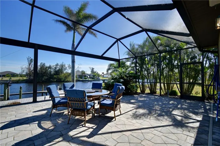 View of patio featuring glass enclosure, a water view, and a boat dock