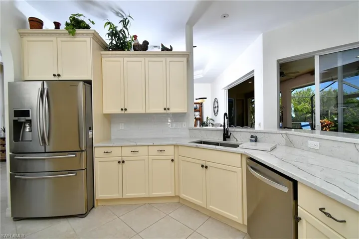 Kitchen with appliances with stainless steel finishes, backsplash, cream cabinets, and sink