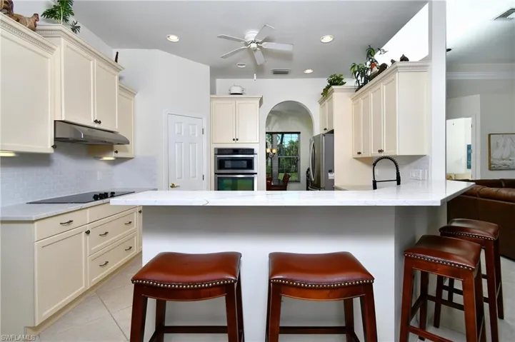 Kitchen with a kitchen bar, cream cabinets, and stainless steel appliances