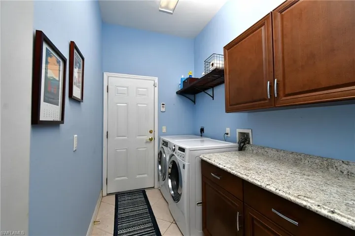 Washroom featuring washer and clothes dryer, cabinets, and light tile patterned floors