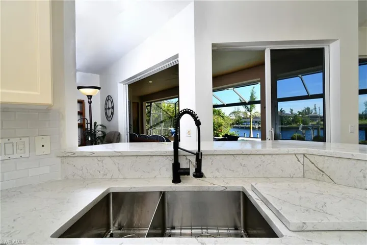 Kitchen featuring decorative backsplash, sink, a water view, and light stone counters