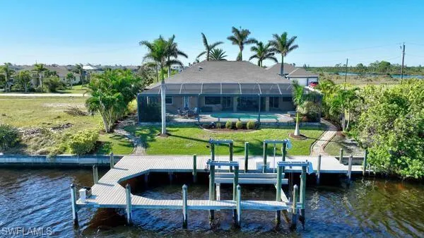 Dock area with a yard, a water view, and a lanai