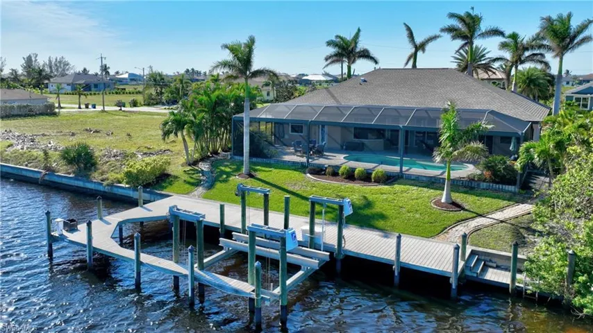 Dock area with a water view, a lanai, and a lawn