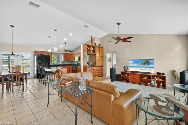 Living area with light tile patterned floors, high vaulted ceiling, ceiling fan, and recessed lighting