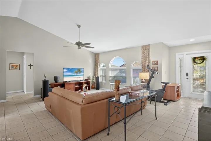 Living area featuring light tile patterned floors, ceiling fan, and high vaulted ceiling