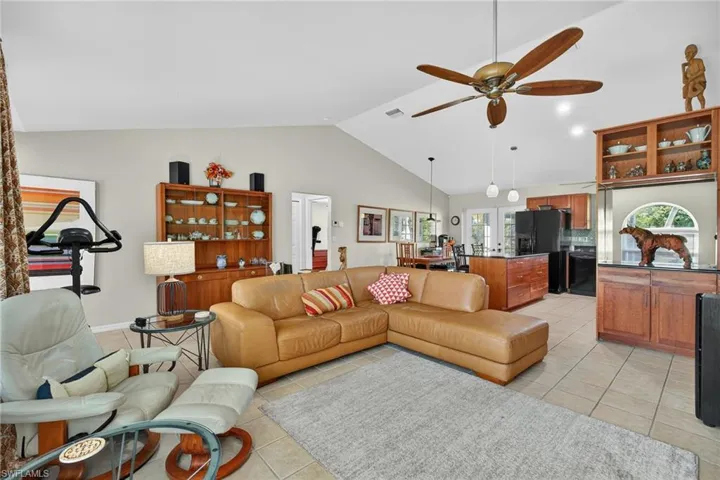 Living area with light tile patterned flooring, a ceiling fan, and high vaulted ceiling