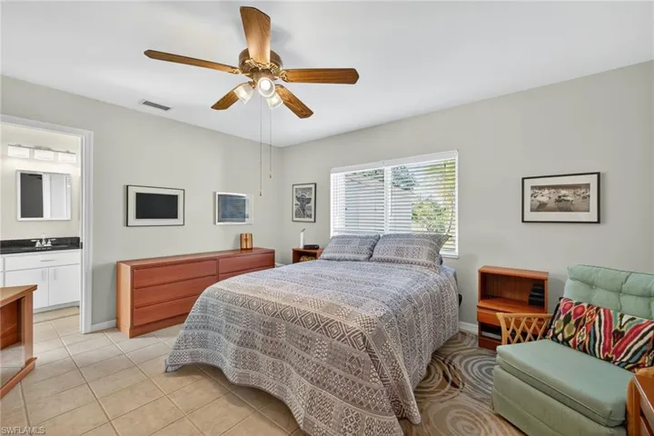 Bedroom featuring light tile patterned floors, ceiling fan, and connected bathroom