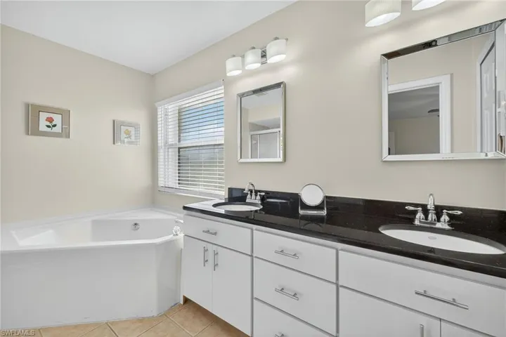 Full bathroom featuring light tile patterned flooring, double vanity, and a bath