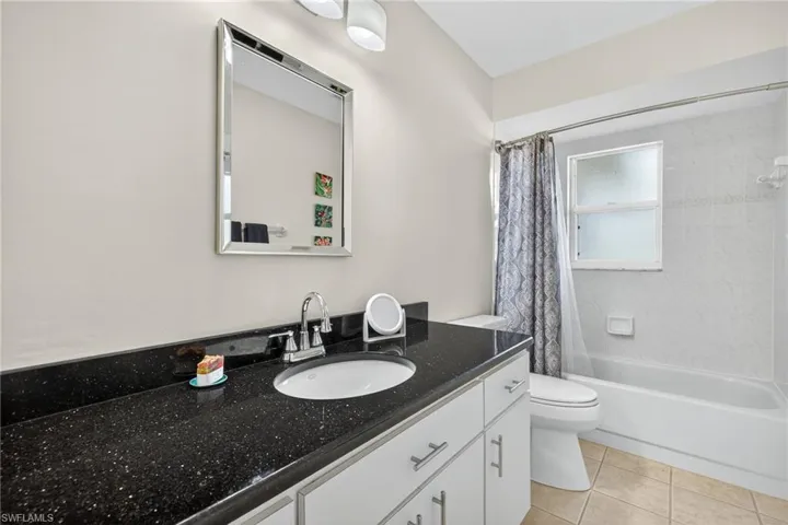Bathroom with vanity, shower / tub combo with curtain, and light tile patterned floors