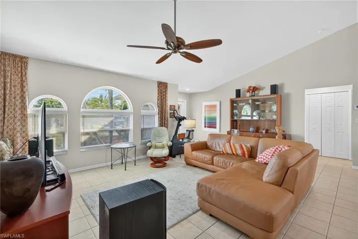 Living room with a ceiling fan, light tile patterned floors, and high vaulted ceiling