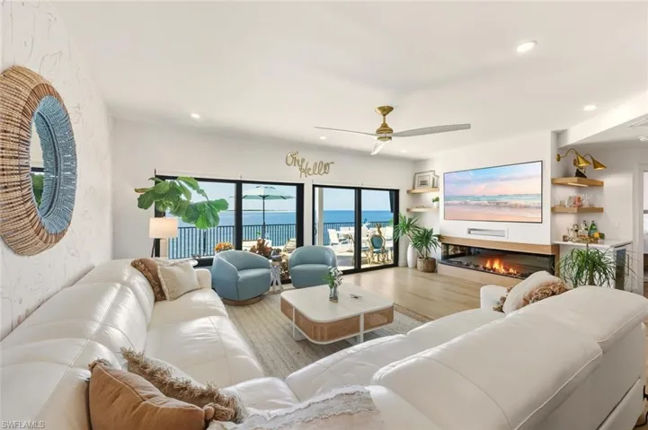 Living area featuring a glass covered fireplace, wood finished floors, recessed lighting, and a ceiling fan