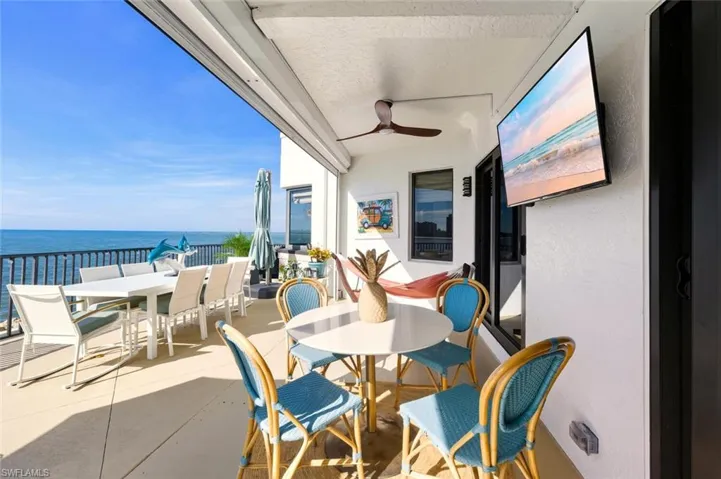 Balcony featuring outdoor dining space, ceiling fan, and a water view