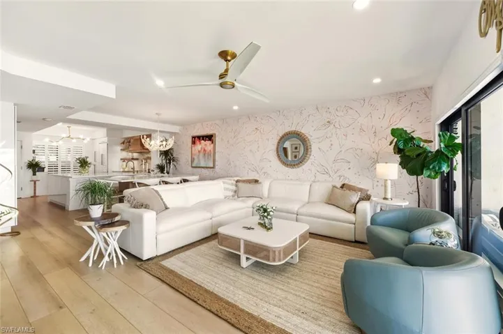 Living area featuring wallpapered walls, a ceiling fan, recessed lighting, light wood-style flooring, and a chandelier