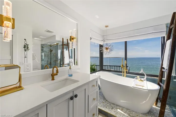 Bathroom featuring vanity, a freestanding bath, a stall shower, and a water view