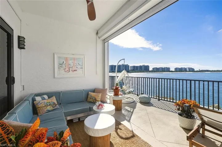 Balcony with a water view, an outdoor living space, and a ceiling fan
