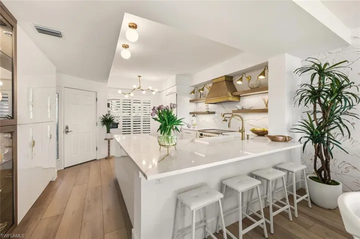 Kitchen with a peninsula, light wood-style flooring, a kitchen bar, and a chandelier