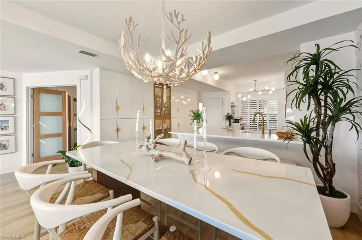 Kitchen with a kitchen breakfast bar, light wood finished floors, light stone counters, and a chandelier