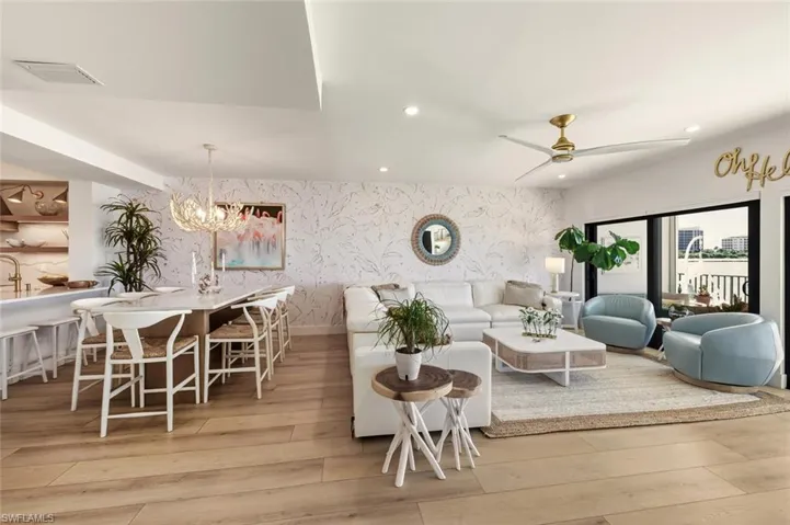 Living room with wallpapered walls, recessed lighting, a chandelier, light wood finished floors, and an accent wall