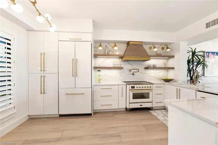 Kitchen with open shelves, premium range hood, white cabinetry, high end appliances, and light stone counters