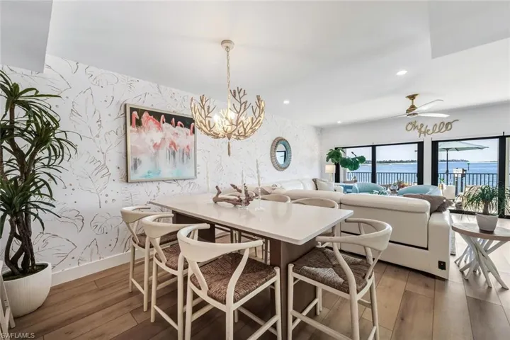 Dining area featuring wallpapered walls, a chandelier, a water view, dark wood-type flooring, and recessed lighting