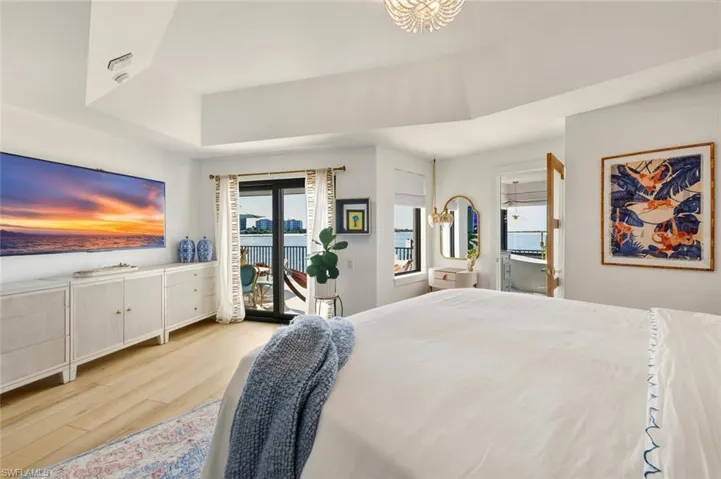 Bedroom with wood finished floors, access to outside, and a chandelier