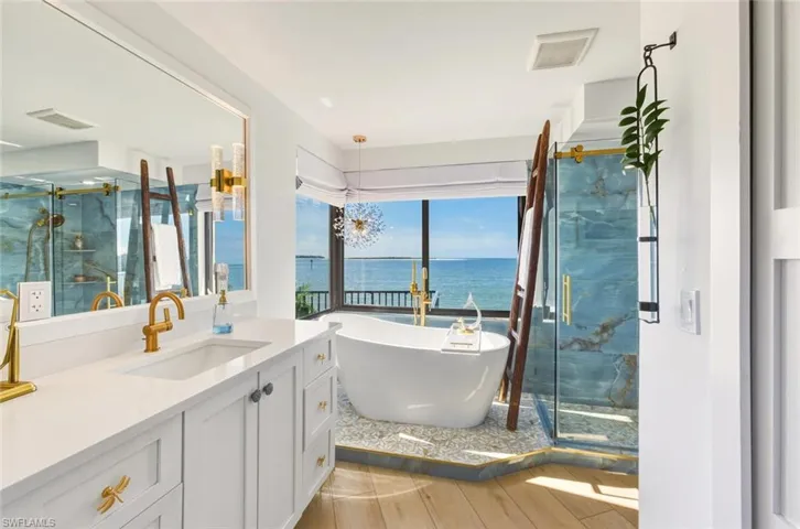 Bathroom with a marble finish shower, vanity, a water view, and a freestanding bath