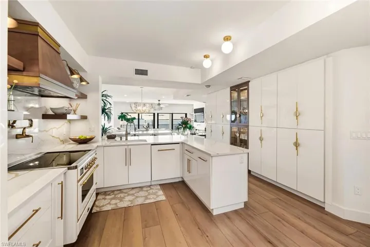 Kitchen featuring high end range, white cabinetry, pendant lighting, and light wood finished floors