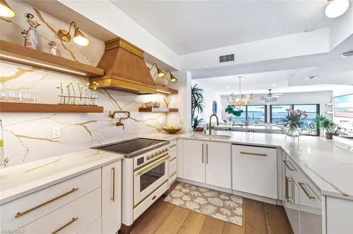 Kitchen with open shelves, high end range, light stone countertops, and custom range hood