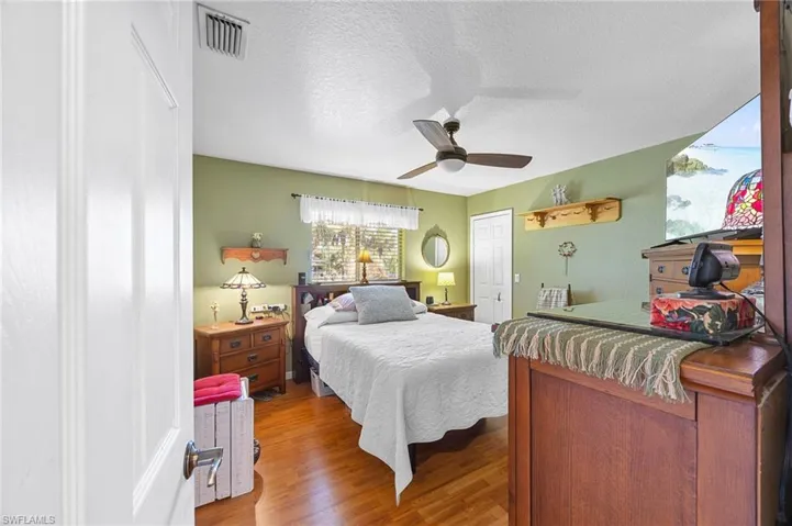 Bedroom with a textured ceiling, wood finished floors, and ceiling fan